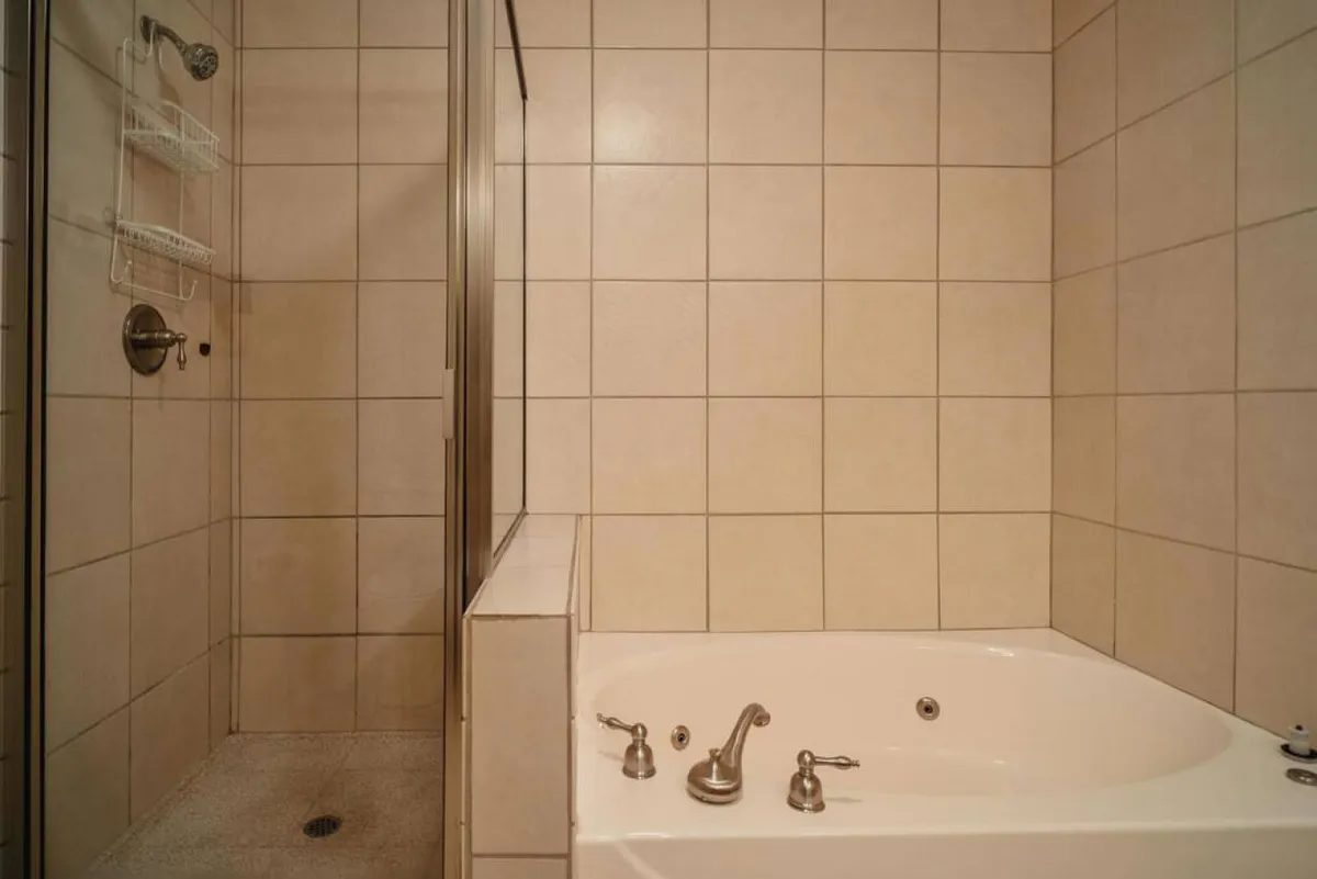 A modern bathroom featuring a spacious bathtub, a separate shower area, and elegant tile work. The mood is calm and serene, suggesting indulgent bathing and moments of quiet self-care.