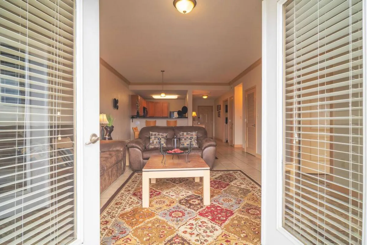 This image centers on a cozy sofa and coffee table set atop an area rug, with a kitchen area visible in the background. The setting is perfect for relaxing, entertaining guests, or coming together for board game nights, capturing the heart of a welcoming home environment.