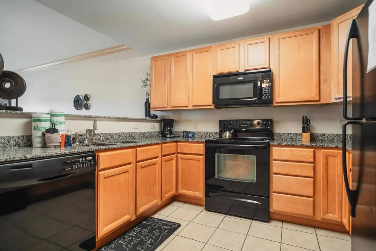A practical kitchen view featuring cabinetry, sleek black appliances, and a granite countertop. The scene is set for baking cookies, prepping breakfast, or whipping up group dinners, with everything within easy reach for hassle-free meal prep.