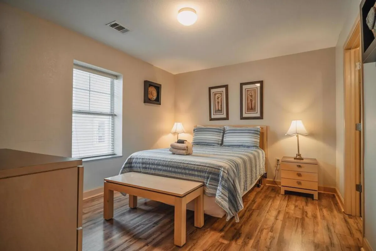 The hero image showcases a serene, sunlit bedroom featuring a plush bed with crisp linens, warm bedside lamps, a stylish nightstand, and inviting artwork, creating a tranquil and welcoming retreat.