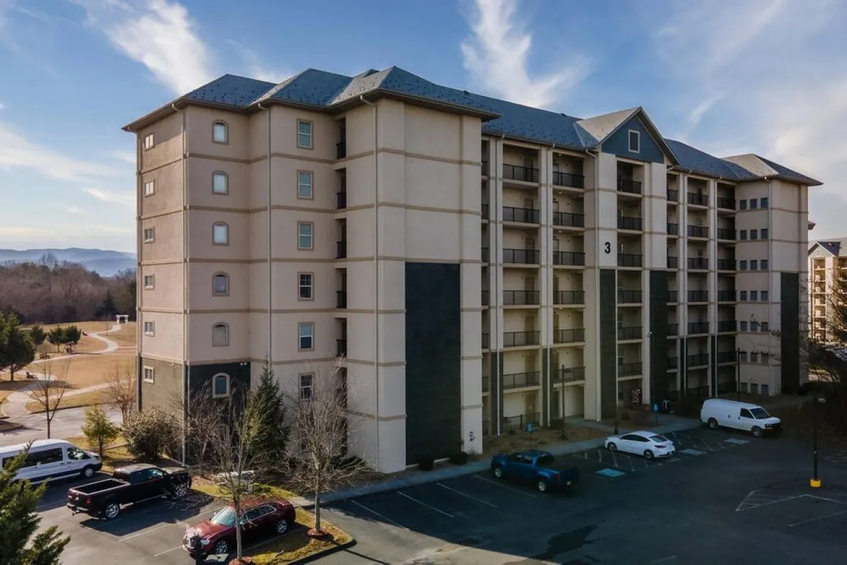 This image captures the building exterior set against the scenic backdrop of mountain views. The parking area and surrounding landscape convey a sense of welcome and easy access to amenities, while the mountains in the distance hint at the opportunity for nature walks and exploration.